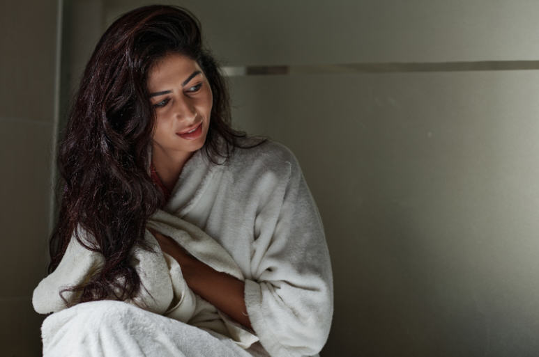 Adult woman sitting calmly in a quiet indoor space, appearing thoughtful and attentive to her body, representing awareness of intimate health symptoms